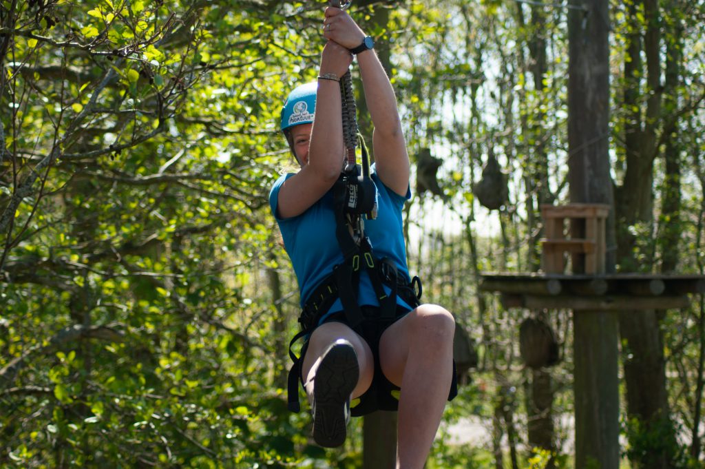 Avontuurlijke dame zweeft moedig op hoge zipline bij klimbos de Klimvallei, Den Helder.